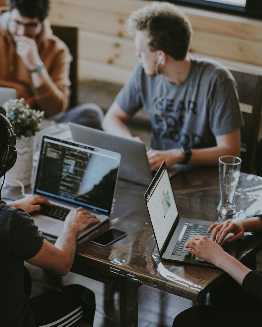 Equipo de trabajo con computadores portátiles abiertos alrededor de una mesa de madera