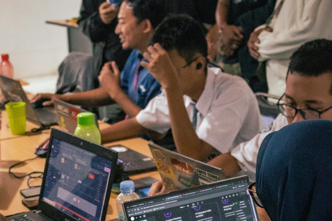 Sala de trabajo con varias personas frente a computadores portátiles con editores de código abiertos