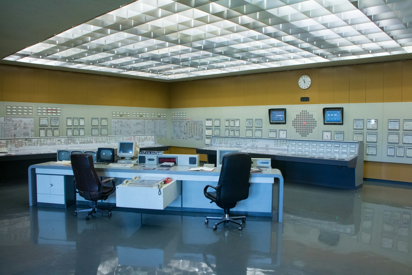 Sala de control industrial vacía, con paneles de instrumentos y dos puestos de operación